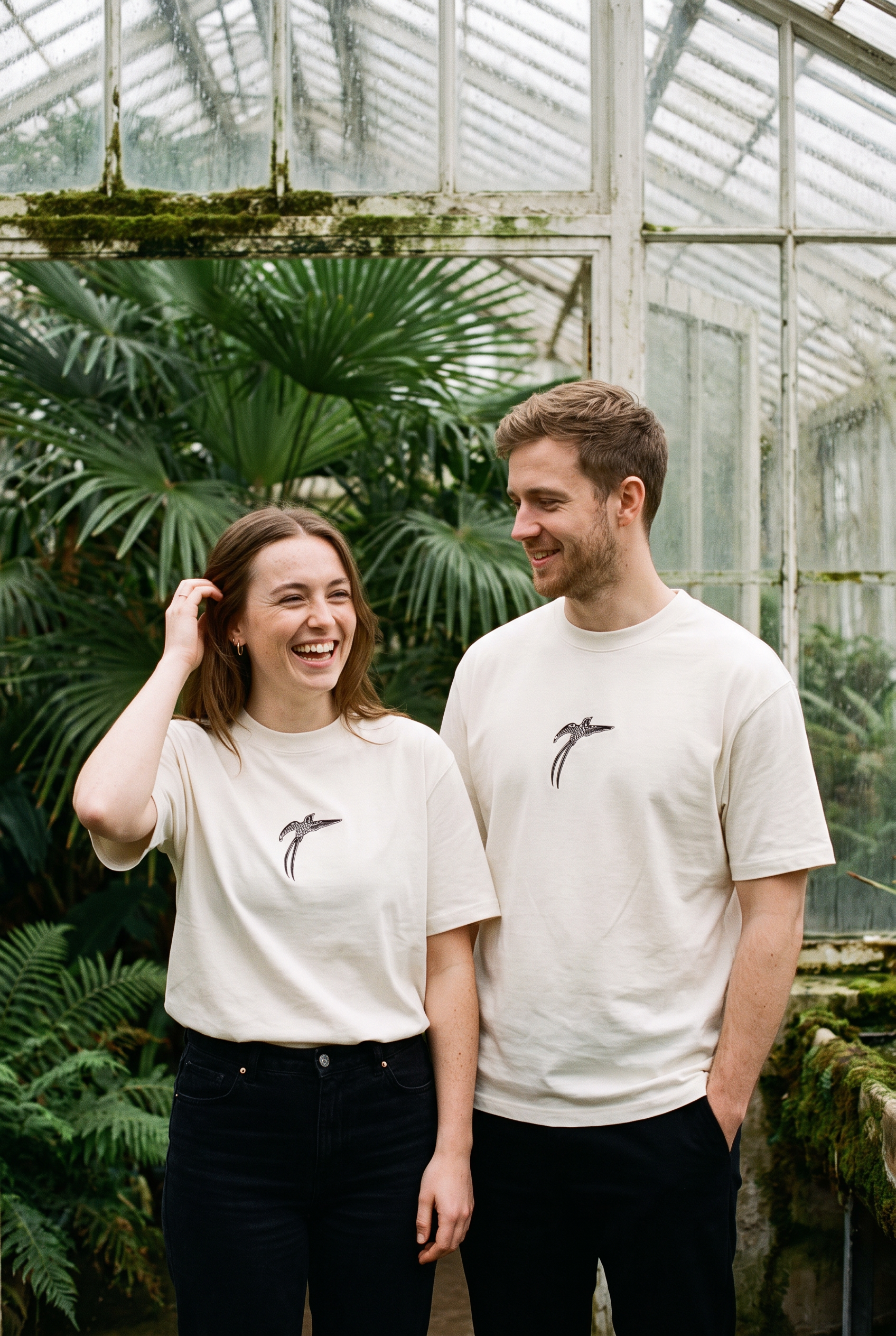 A man and woman both wearing the white Bird of Paradise tee