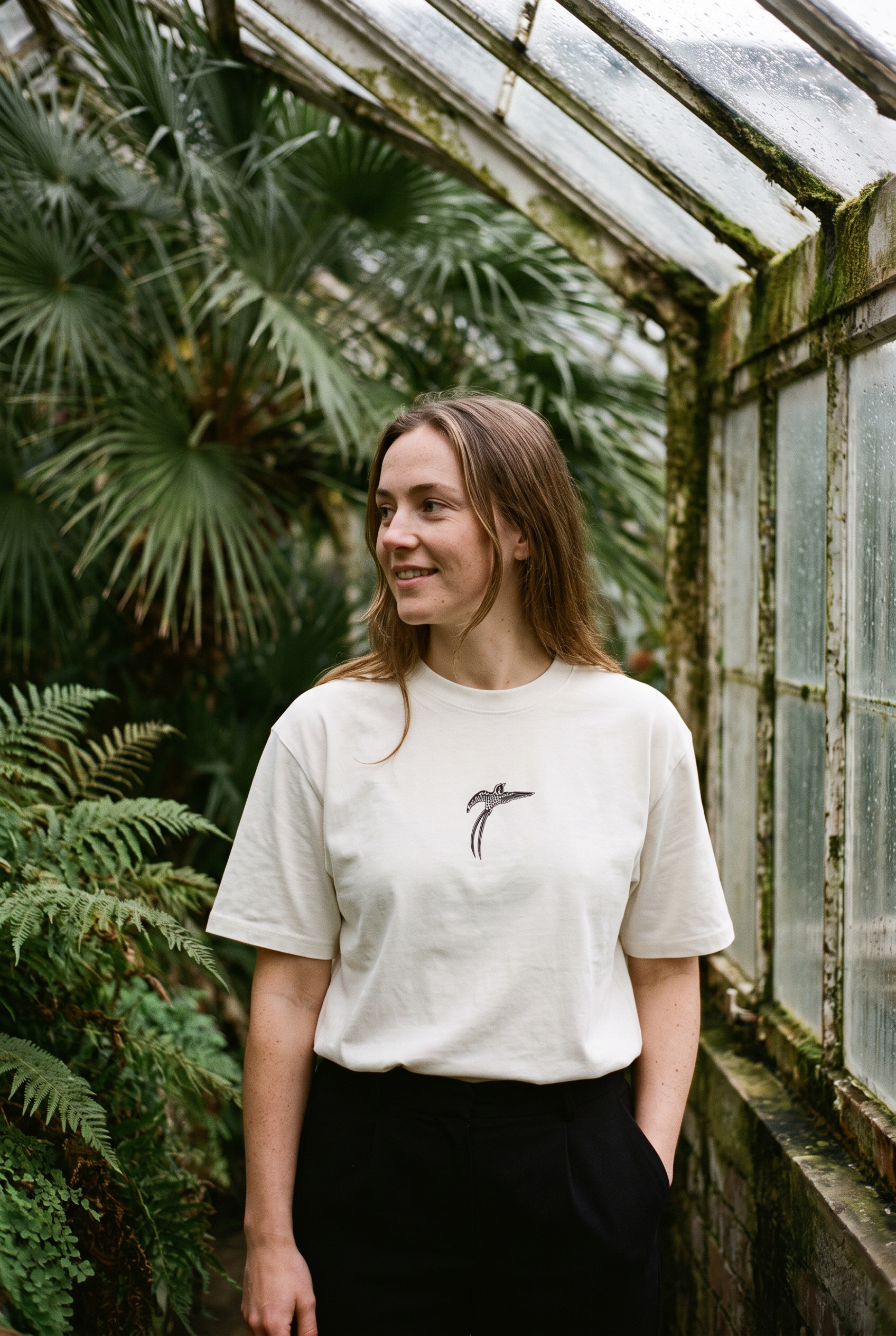 Woman wearing the white Bird of Paradise tee in a Victorian glasshouse