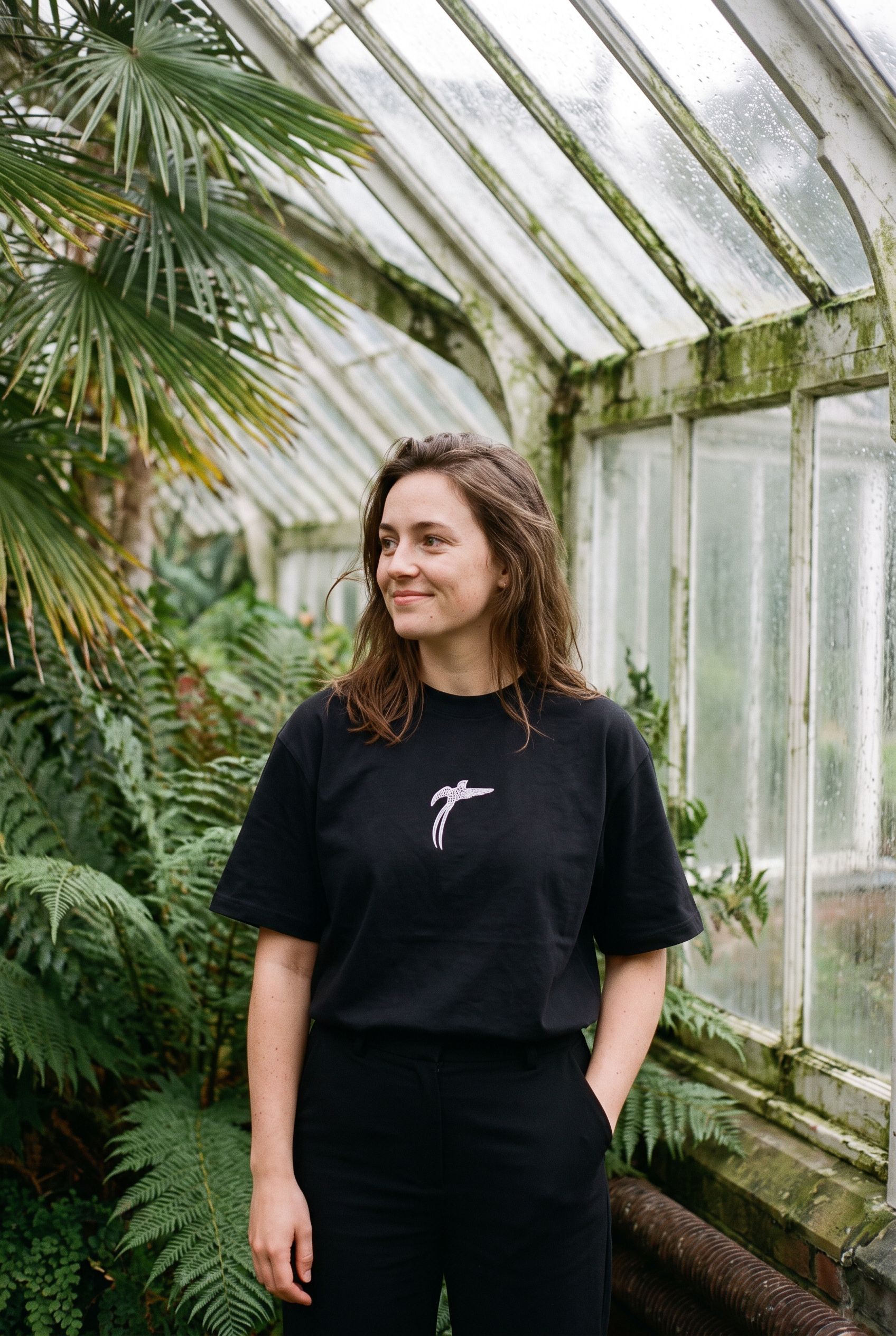 Woman wearing the black Bird of Paradise tee in a Victorian glasshouse